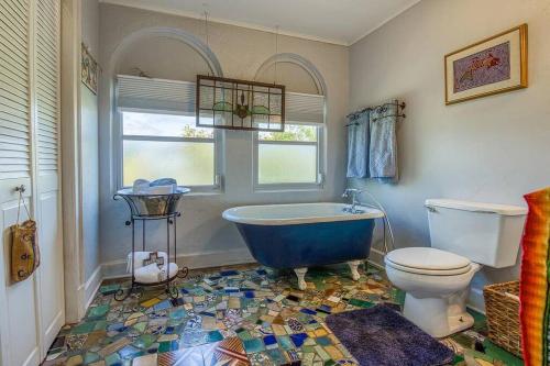 y baño con bañera azul y aseo. en Charming Villa Espagna - Heated/Salt-Pool Oasis!, en Lake Worth