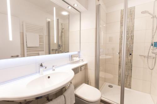 a white bathroom with a sink and a shower at Hotel Bavaria Oldenburg in Oldenburg