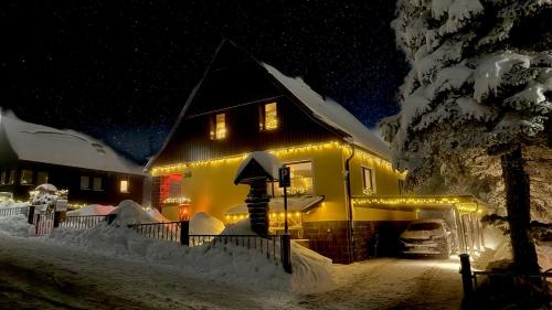 a house covered in snow at night with lights at Ferienwohnung-direkt-am-Skihang mit Sauna in Kurort Oberwiesenthal