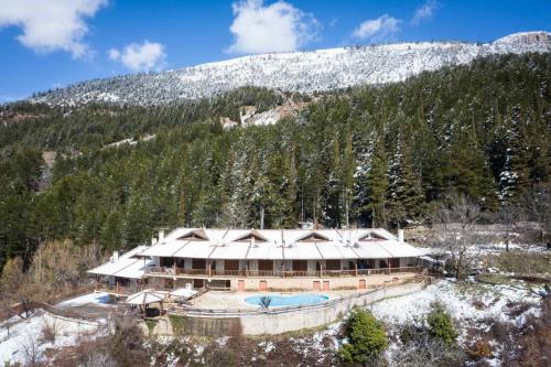 a large building in front of a snow covered mountain at Helmos Mountain Retreat in Zarouhla