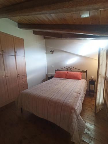 a bedroom with a bed with a red pillow at Helmos Mountain Retreat in Zarouhla