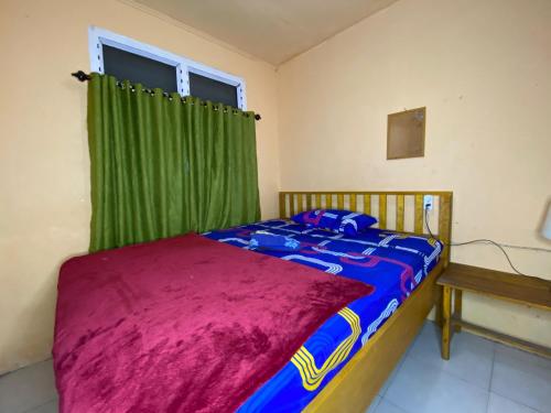 Harry & Mimin Homestay في جورونتالو: غرفة نوم بسرير وستارة خضراء