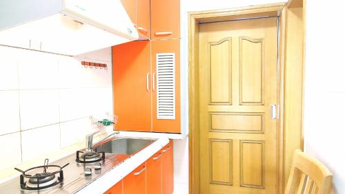 uma cozinha com uma porta laranja e um lavatório em Lily's home em Xangai
