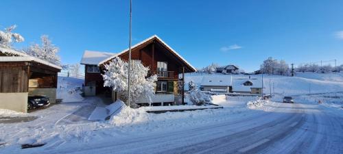 a house is covered in snow next to a road at Naturnahe Familienwohnung in Rüschegg-Graben