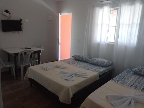 佩羅巴的住宿－Casa morada da praia 5，酒店客房设有两张床、一张桌子和一张桌子。