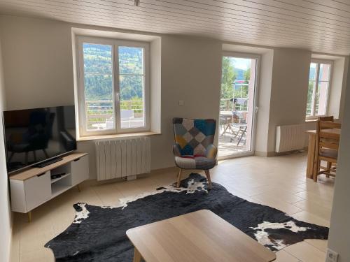 een woonkamer met een stoel en een tv bij La Maison Rose - La Bresse in La Bresse