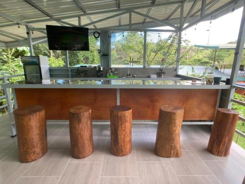 a bar with four wooden stools in front of it at Yejos in Dos Brazos