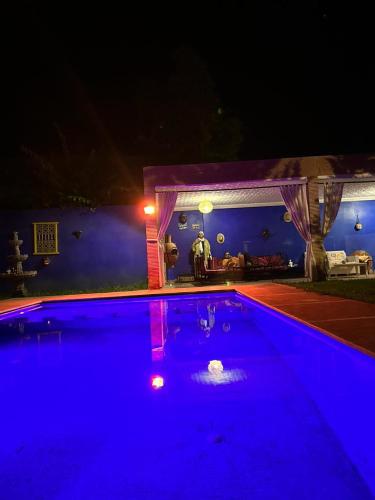 a man standing next to a swimming pool at night at Paradise house in Marrakech