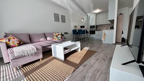 a living room with a purple couch and a kitchen at Lucky Homes Apartment Kosice in Košice