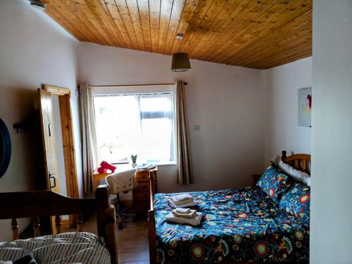 Schlafzimmer mit einem Bett, einem Tisch und einem Fenster in der Unterkunft Sunriseview Cottages in Wicklow