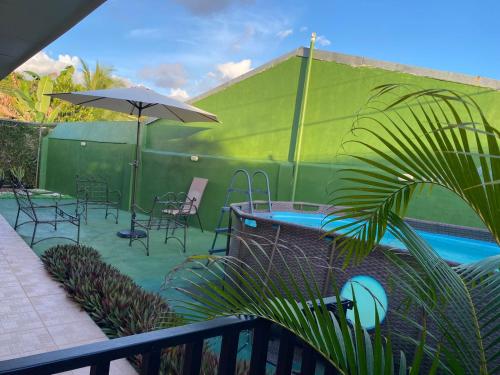 a patio with a pool and chairs and an umbrella at Casa Brisa Marina, Comfy Villa for 7 with Private Pool, Just 10 Minutes from Manuel Antonio! in Quepos