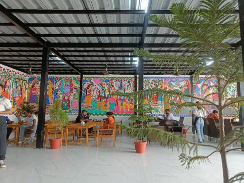 een restaurant met mensen aan tafel voor een muurschildering bij Mithila Thali By Chef Santosh Shah in Janakpur