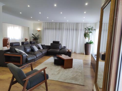 a living room with a black couch and a table at Casa com piscina para 10 pessoas - 5 min da praia Esposende in Esposende