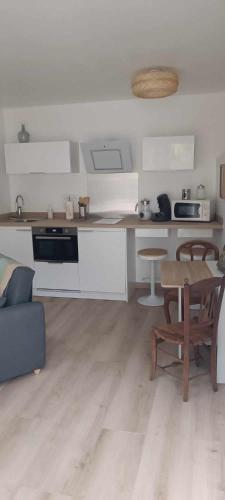 a kitchen with white cabinets and a wooden table at L'appentis in Bligny-lès-Beaune
