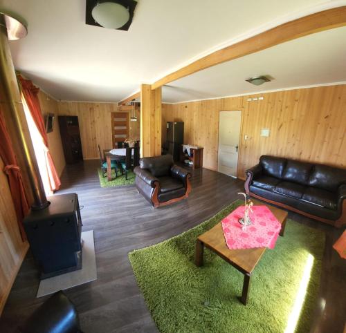 a living room with a leather couch and a table at Cabaña Alto Naupe in Puerto Saavedra