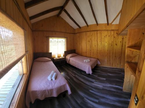 een kamer met 2 bedden in een houten hut bij Cabaña Alto Naupe in Puerto Saavedra
