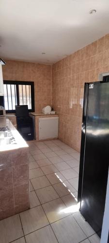 a kitchen with a black refrigerator in a room at Villa Massai avec piscine au cœur de Saly in Sali Nianiaral
