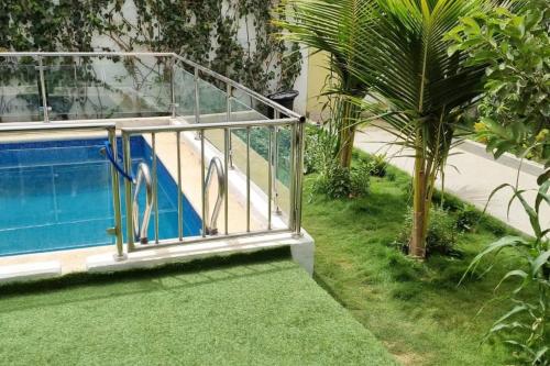 a pool with a metal railing next to a palm tree at Villa Massai avec piscine au cœur de Saly in Sali Nianiaral
