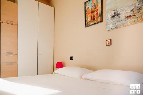 a bedroom with a white bed and a cabinet at THE BEACH by Design Studio in Bellano
