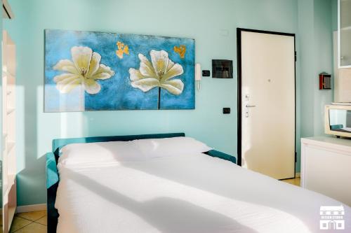 ベッラーノにあるTHE BEACH by Design Studioの白いベッドと壁に絵画が飾られたベッドルーム1室