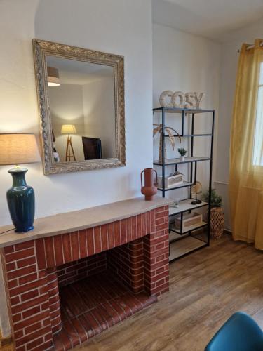 ein Wohnzimmer mit einem gemauerten Kamin und einem Spiegel in der Unterkunft Grand appartement cosy-Hyper Centre-Place Verdun in Tarbes