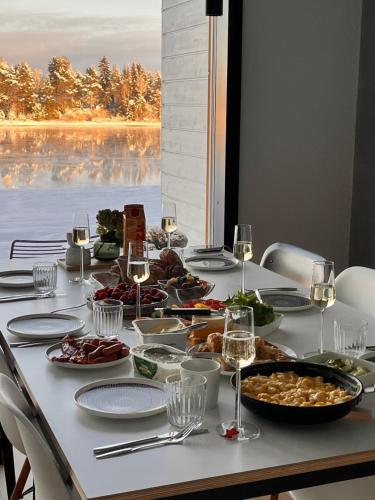 a table with plates of food and glasses of wine at Arctic Riverside Villa in Rovaniemi