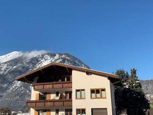 a building with a snow covered mountain in the background at Ferienwohnungen Hechenblaikner in Maurach