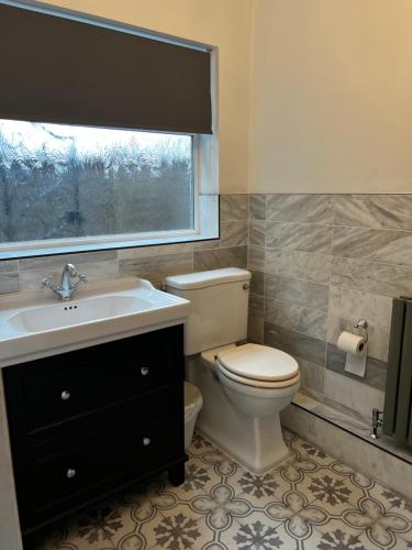 a bathroom with a toilet and a sink and a window at Dartford Stay in Kent