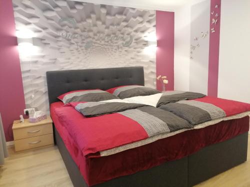 - une chambre dotée d'un lit avec une couverture rouge et grise dans l'établissement Ferienwohnung Jurk, à Bärenstein