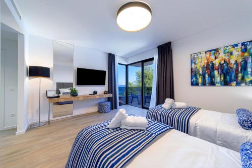 a bedroom with two beds and a television in it at Villas Lucy - 1 Lemon -outdoor pool , 2 Cherry-indoor pool and 3 Plum-outdoor pool in Marina