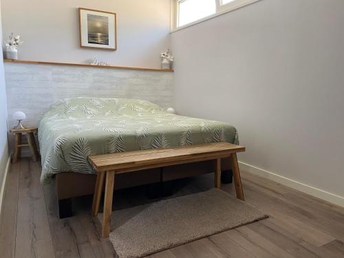 een bed in een kamer met een houten tafel bij Bungalow Scheldezicht in Zeeland dicht bij zee in Scherpenisse
