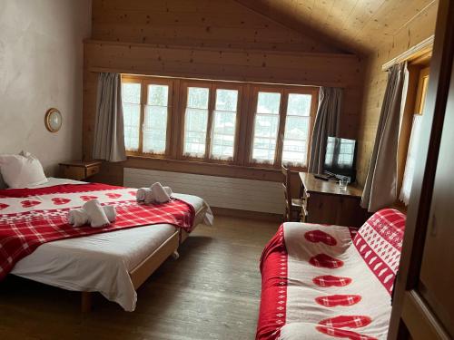 a hotel room with two beds and a television at L'Auberge de L'Ours in Vers L'Eglise