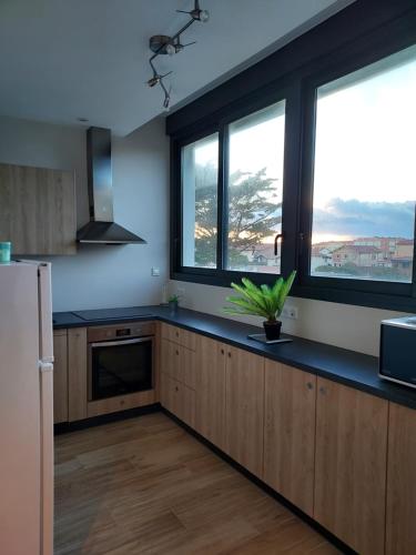 - une cuisine avec des placards en bois et 2 grandes fenêtres dans l'établissement Appartement Mimizan Plage accès direct plage surveillée, à Mimizan