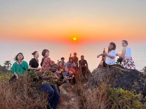 a group of people sitting on a rock at sunset at Mitra Hostel in Arambol