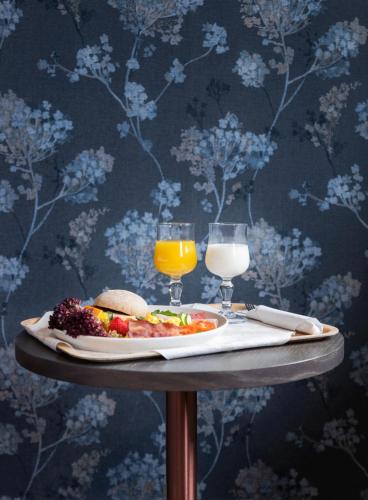 a table with a plate of food and two glasses of orange juice at Milepelen Hotel & Vertshus in Sand