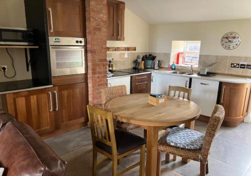 a kitchen with a wooden table and chairs in it at Inglenook Cottage in Wandylaw