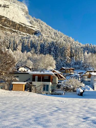 a group of houses in the snow in front of a mountain at s'pölven NEST in Bad Häring