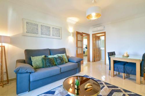 a living room with a blue couch and a table at Apartamento Moderno Albufeira L14 in Albufeira