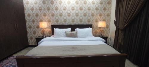 a bedroom with a large bed with two lamps at Hotel Daffodils in Rawalpindi