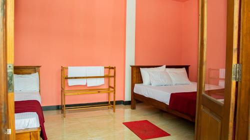 two beds in a room with pink walls at Bougainvillea Resort in Bandarawela