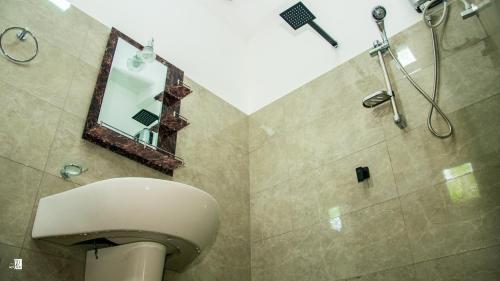 a bathroom with a toilet and a mirror and a shower at Bougainvillea Resort in Bandarawela
