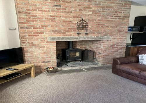 a living room with a brick fireplace with a couch at Inglenook Cottage in Wandylaw