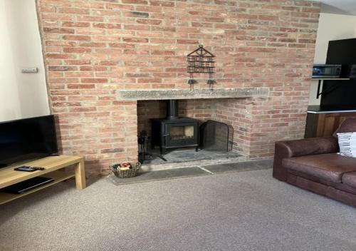 sala de estar con chimenea de ladrillo y sofá en Inglenook Cottage, en Wandylaw