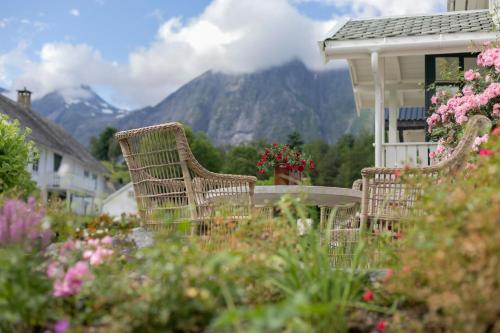 a table and chairs in a garden with mountains in the background at Østigård 1810 in Åndalsnes