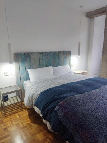 a bedroom with a bed with a blue blanket at La cámara secreta de BelNi in Avilés
