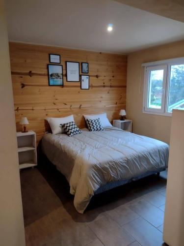 a bedroom with a large bed with a wooden wall at Baguales Alojamientos Patagonicos in Villa La Angostura