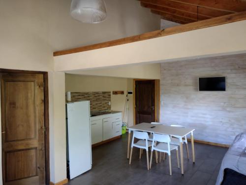 a kitchen with a table and a white refrigerator at Baguales Alojamientos Patagonicos in Villa La Angostura
