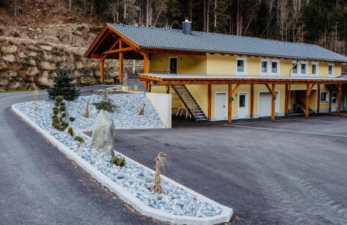 ein großes gelbes Gebäude mit einem Haus in der Unterkunft Ferienwohnung Sabine in Flattach