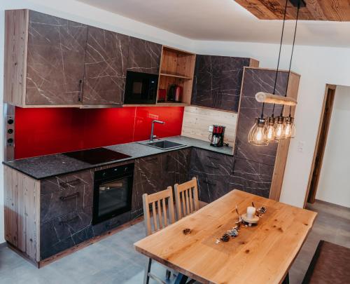 a kitchen with a wooden table and a red wall at Ferienwohnung Sabine in Flattach