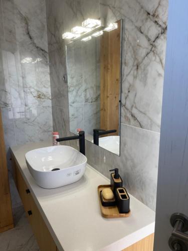 uma casa de banho com um lavatório branco e um espelho. em Къща за гости Лиственица 1 em Banya